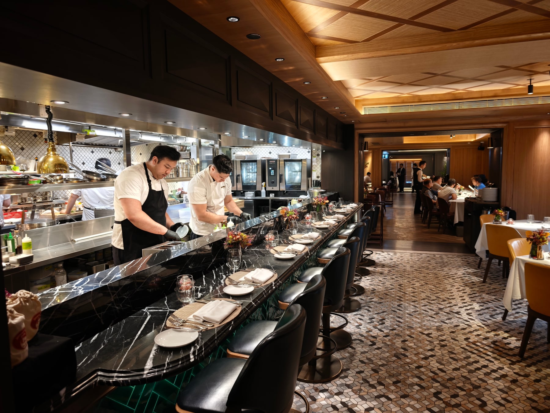 木の天井と黒い大理石のカウンターが続くJimmy's Kitchinの店内。カウンター越しに調理するスタッフの姿が見える