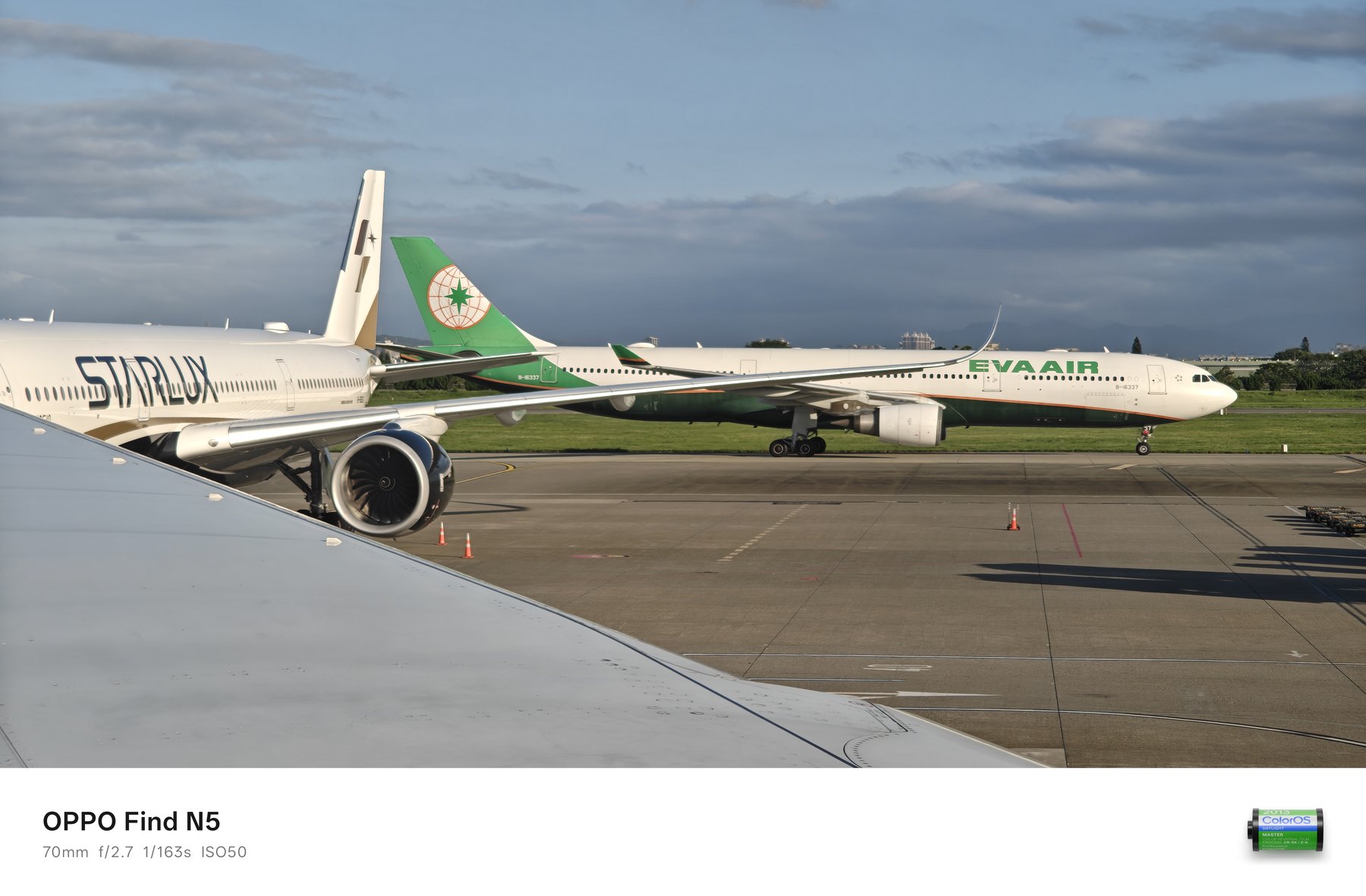 台北・桃園空港で、機窓から自機の翼越しに見た、手前のスターラックス機と、奥の誘導路を行く緑の尾翼のエバー航空機