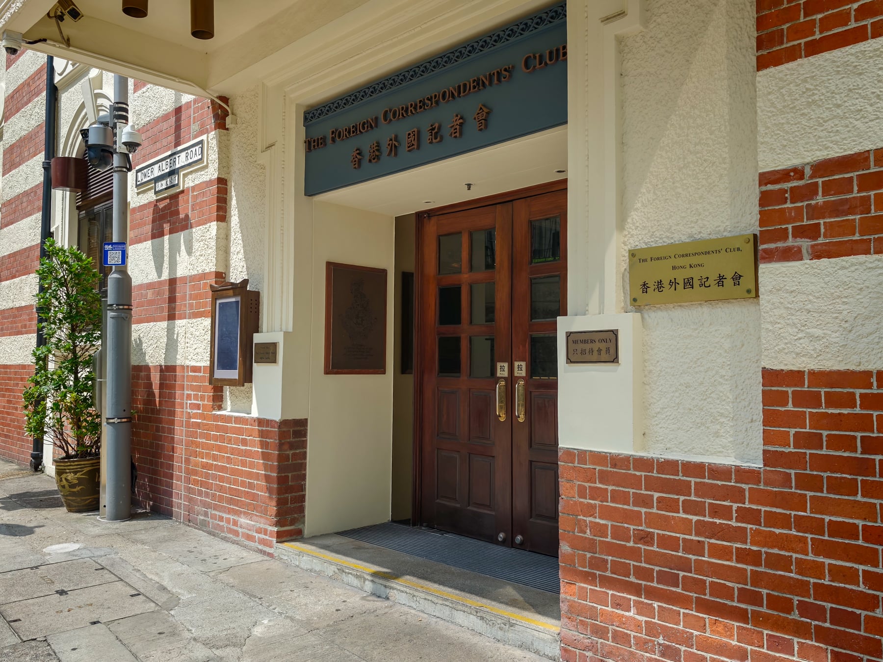 赤れんがと白い壁に囲まれたFCCの木製の入口。扉の上にTHE FOREIGN CORRESPONDENTS' CLUBの文字がある