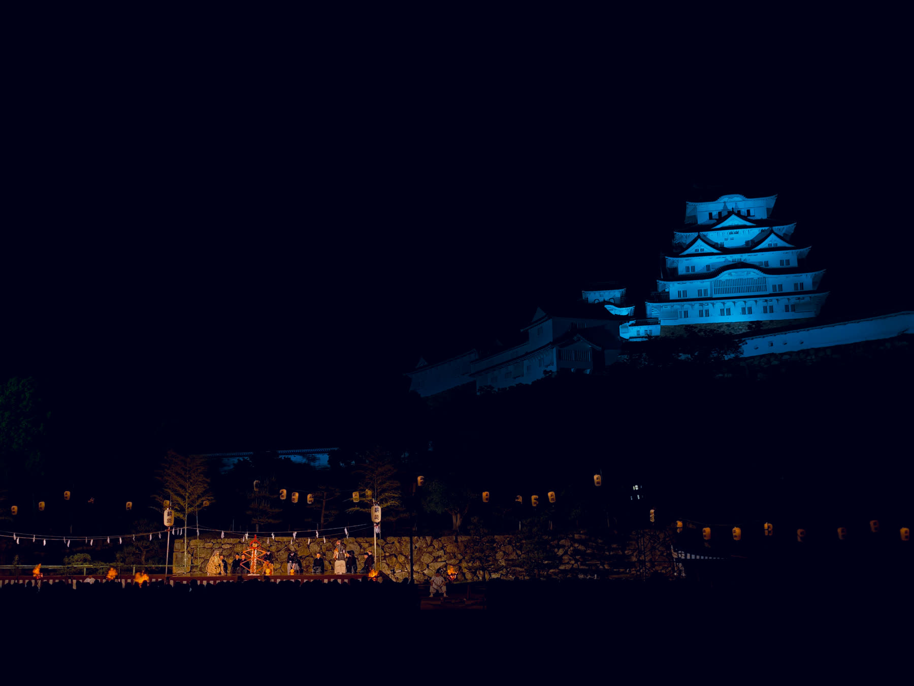 姫路城の天守の下、三の丸広場で薪能の舞台が行われている夜景