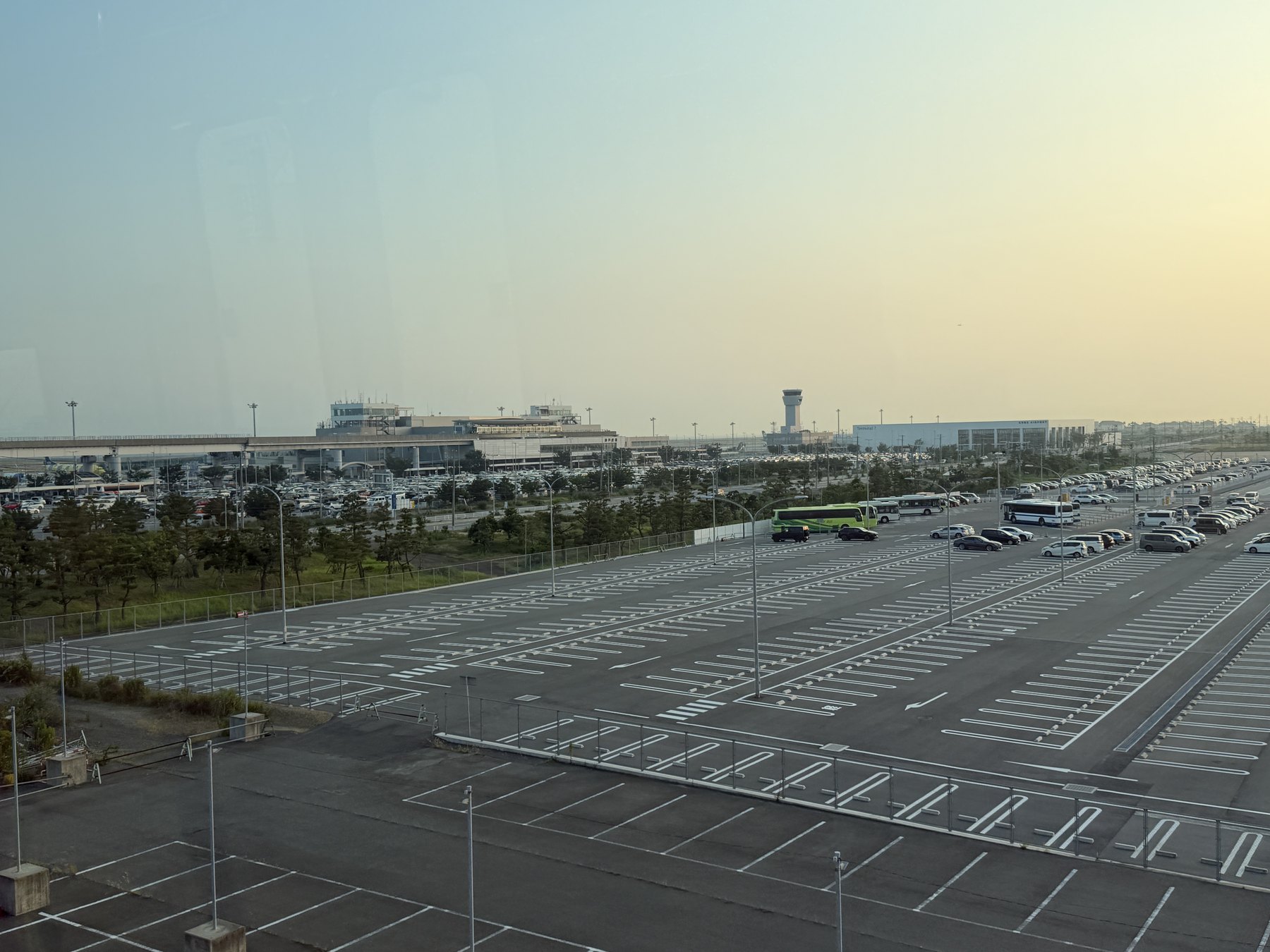 ポートライナーの車窓から見返す夕暮れの神戸空港。ターミナル1と管制塔、右手に新しいターミナル2