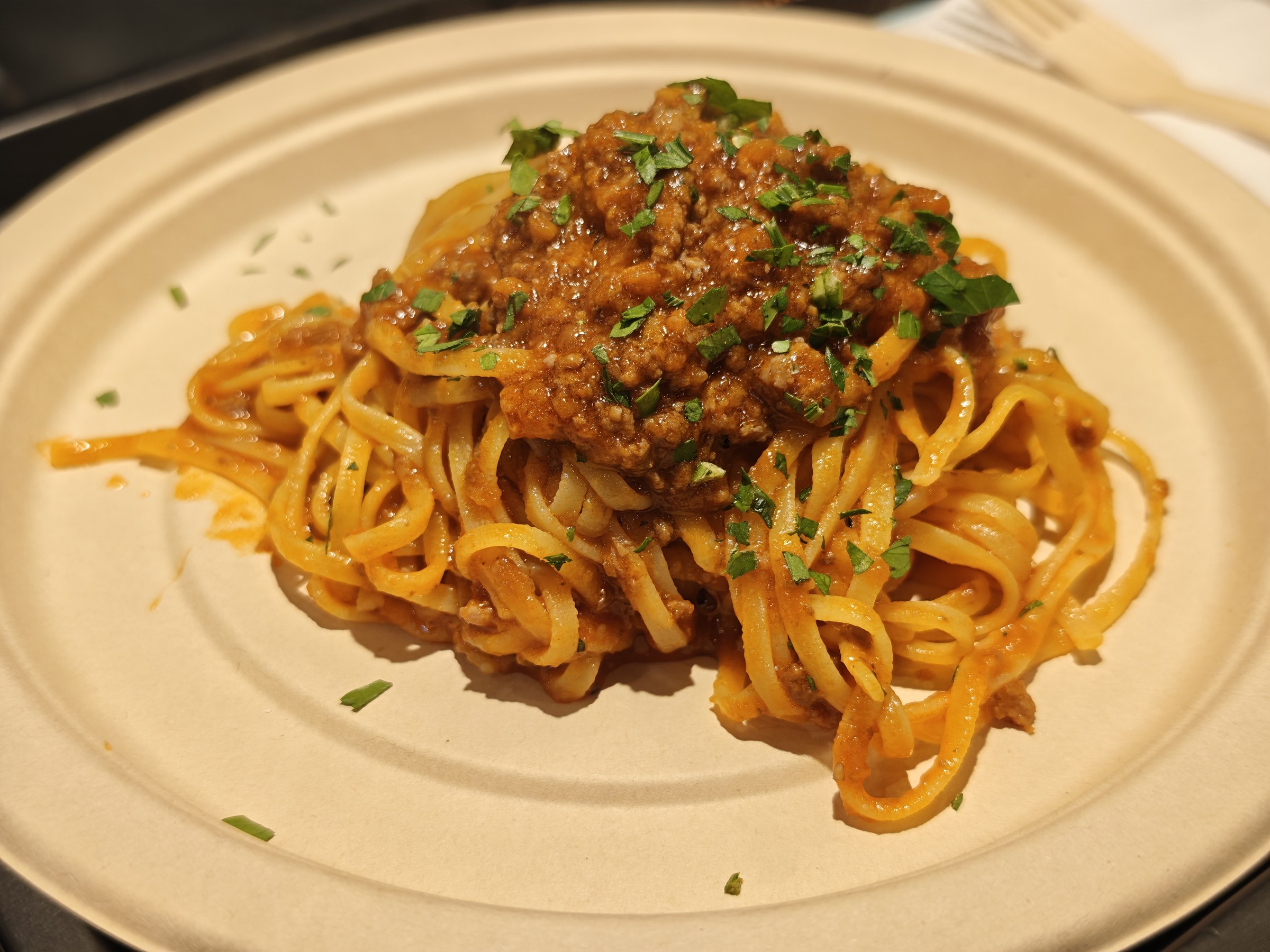 紙皿に盛られたボロネーゼのパスタ