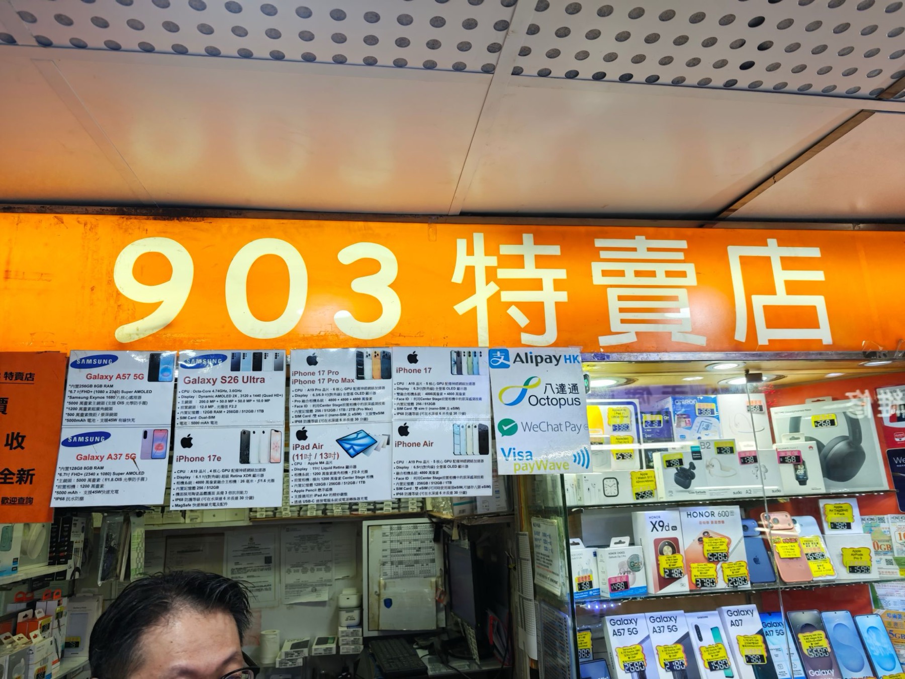 先達廣場の903特賣店。最新スマホのスペック表と支払い方法のステッカーが並ぶ店頭