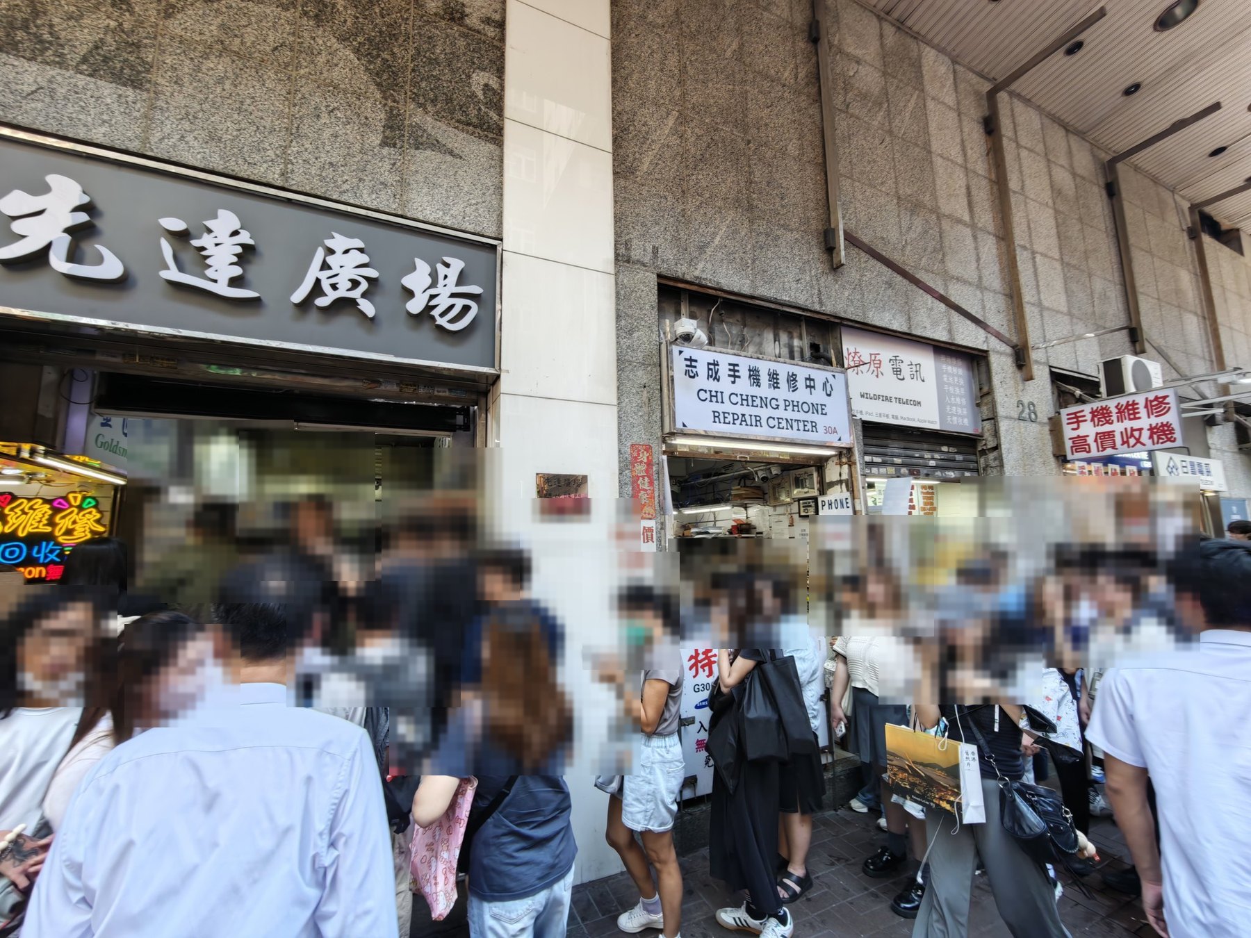 「先達廣場」の看板の下、入口の前に人がぎっしりと集まり、中へ入れなくなっている