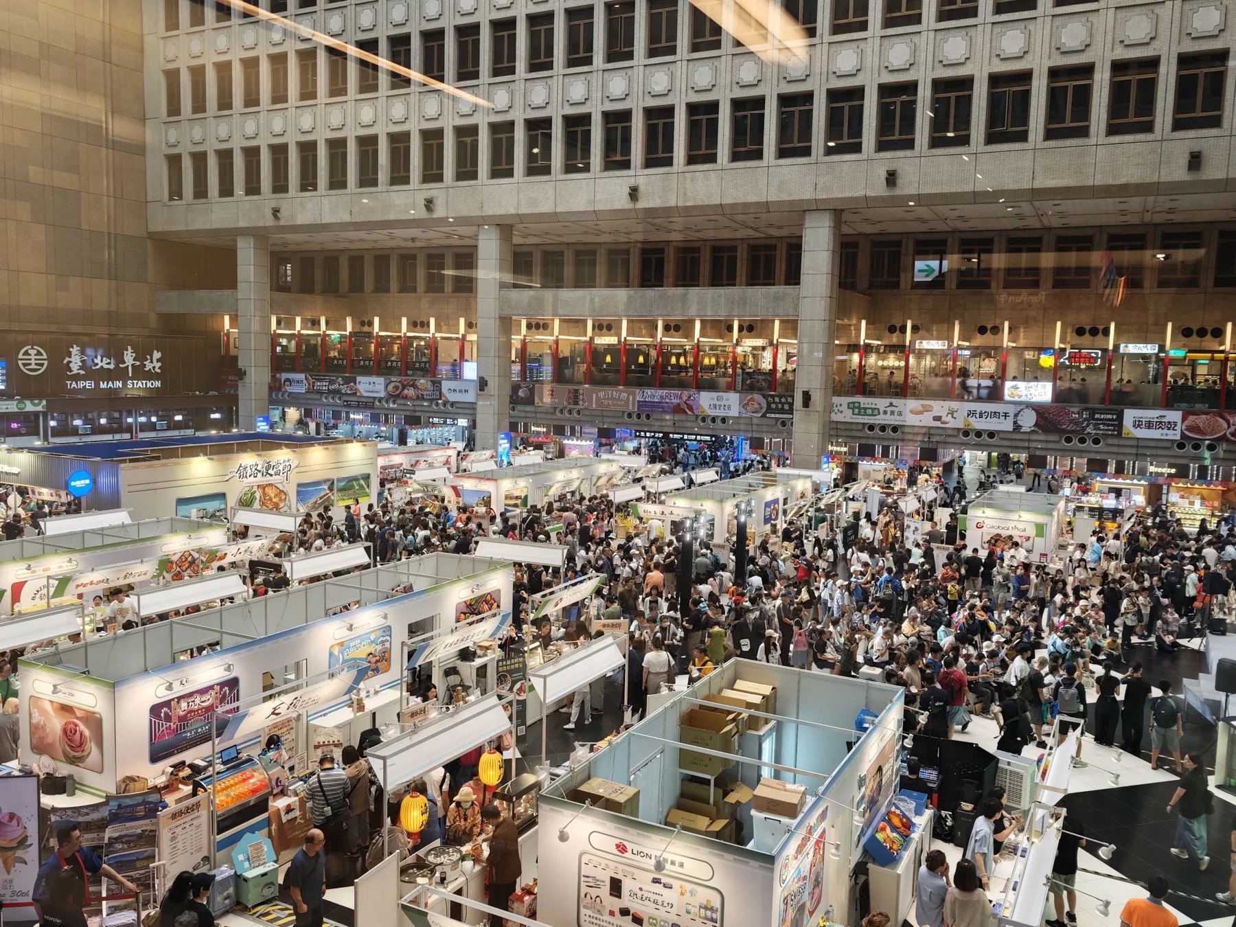 台北駅の広いホールに弁当フェアのブースと多くの来場者が集まっている様子