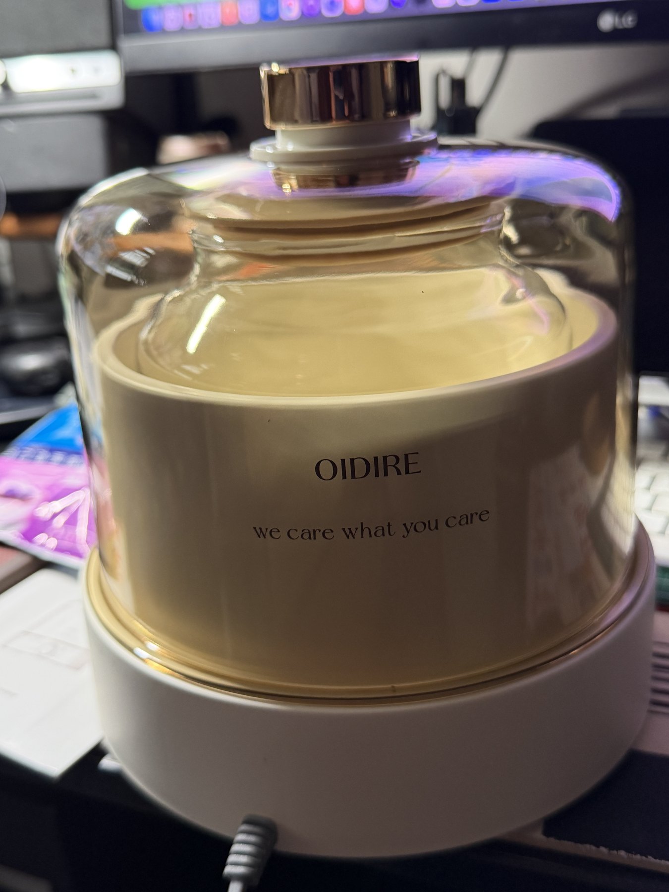 OIDIRE と刻まれたヨーグルトメーカー。ガラスのドームの中で牛乳が黄金色に発酵し、机の上でモニターの光を背にしている。