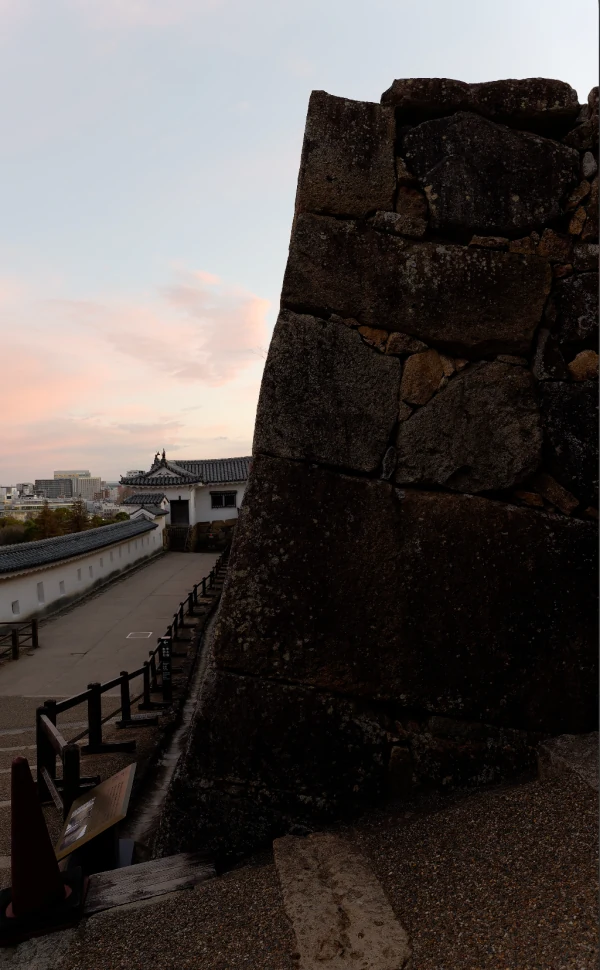 夕空と城内の通路を背景に、手前に大きく写る備前門脇の石垣の角。石棺を転用した石のある場所を、周囲の景色とともに撮影。