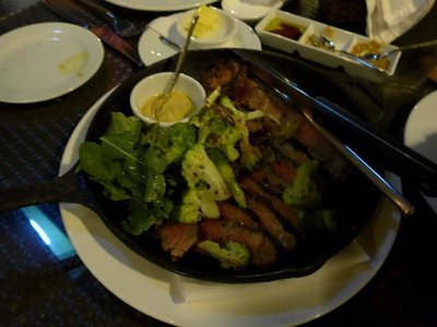 黒い鉄板に載ったリブアイステーキと、添えられたサラダ