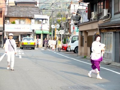 祇園の通り。舞妓姿の人が歩き、タクシーが走っている