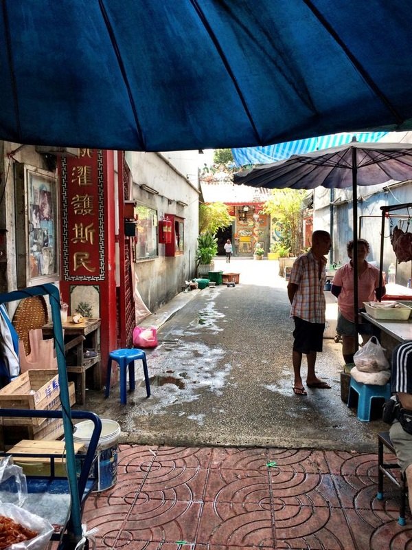 中華街の路地。青いテントの下に屋台が出て、突き当たりに廟が見える