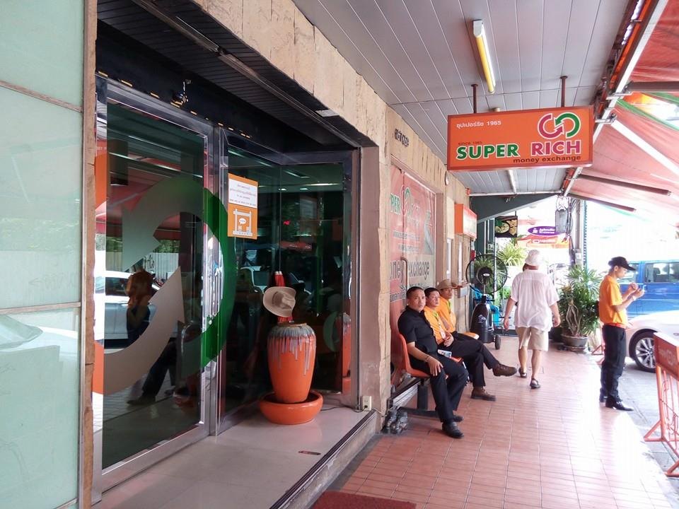 オレンジ色の看板の Super Rich money exchange の店構え。店員が入口の脇に座っている